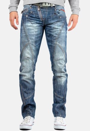 Blauwe denim jeans met een slim fit, vervaagde afwerking en asymmetrische stikseldetails. Bevat meerdere zakken en een ritssluiting.