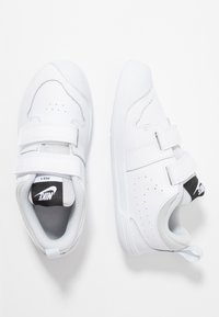 Białe sneakersy Nike z gładką skórzaną powierzchnią, dwoma paskami na rzepy, perforowanymi detalami oraz szarym siateczkowym wykończeniem.