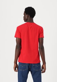 Rød t-shirt med korte ærmer lavet af bomuld, med en rund halsudskæring og en glat tekstur. Kombinationen med blå denimjeans giver et afslappet look.