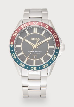 Montre en acier inoxydable argenté avec un cadran rond gris, des accents dorés et une lunette bi-tons bordeaux et teal. Comprend un affichage de la date et des marqueurs luminescents.