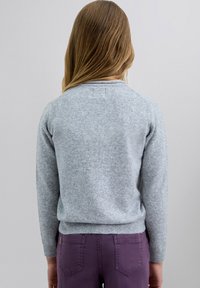 Suéter de punto gris con un cuello redondo y puños acanalados, combinado con jeans morados. La textura parece suave con un acabado ligeramente peludo.