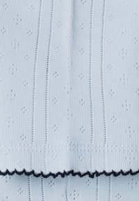 Tela de punto azul claro con canalé vertical, que presenta pequeños patrones de diamantes y un dobladillo en forma de ondas en azul oscuro. Textura suave.