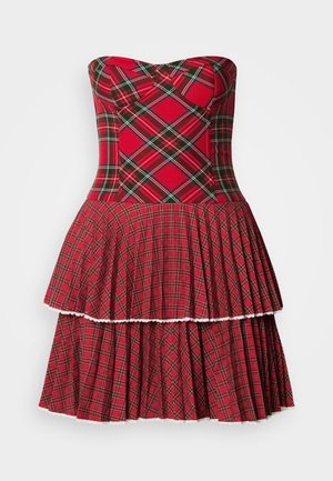Rochie fără mâneci cu carouri roșii, având un corset ajustat și o fustă înclăcată cu pliseuri și bordură zimțată, fabricată dintr-un amestec de bumbac.