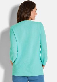 Helles türkisfarbenes Sweatshirt mit Rundhalsausschnitt und Dreiviertelärmeln, aus einem glatten Strickstoff mit geripptem Saum gefertigt.