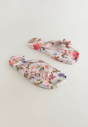 Ziedu stilā flip-flopi ar rozā loku. Zole ir ar baltu fonu, ko rotā krāsaini ziedi un uzdrukāts vārds "BAK". Teksturēta zolīte.