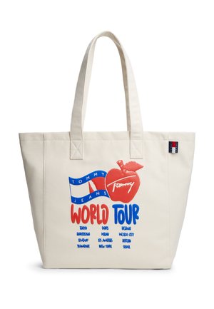 Hvid tote-taske med to håndtag med rød og blå "Tommy Jeans World Tour" tekst, et rødt æblegrafik og en liste over større byer.