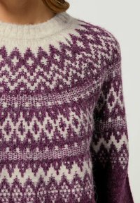 Strickpullover mit einem lila und weißen geometrischen Muster, rundem Ausschnitt, gerippten Bündchen und einer weichen, flauschigen Textur.