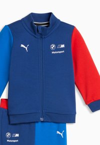 Σετ παιδικά πουλόβερ με φερμουάρ και παντελόνι σε μπλε, κόκκινο και ναυτικό χρώμα, με λογότυπα BMW Motorsport και Puma στο μπροστινό μέρος.