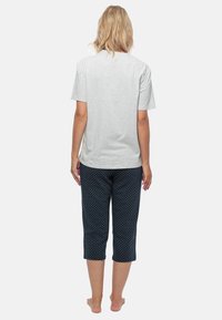 Grijze katoenen t-shirt met korte mouwen, gecombineerd met marineblauwe cropped broek met witte stippen, gezien vanaf de achterkant.