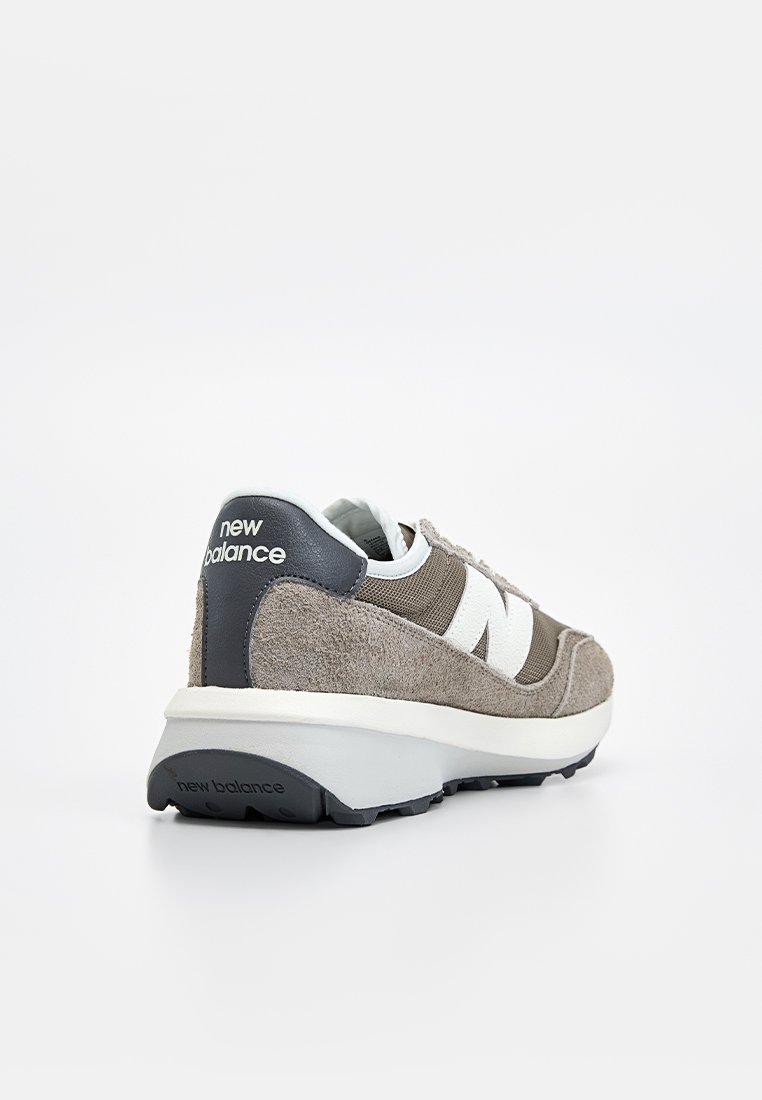 Grauer Sneaker aus Wildleder und Mesh mit weißen Akzenten, ausgestattet mit einer gepolsterten Sohle und einer Zuglasche hinten, gebrandetem Fersenpatch und strukturierten Überzügen.