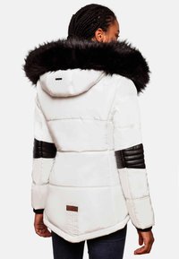 White puffer jacket with a black faux fur hood. Features a quilted pattern, black leather accents on sleeves, and a branded tag at the back.
