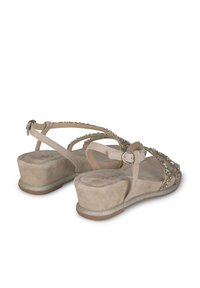 Sandali beige in suede con una finitura testurizzata, caratterizzati da accenti decorativi in perline, una suola a zeppa bassa e cinturini regolabili con chiusura a fibbia.