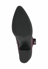 Suela de un zapato de goma negra con un patrón de agarre texturizado; presenta un extremo redondeado y un pequeño tacón cuadrado; parte superior de ante púrpura no visible.