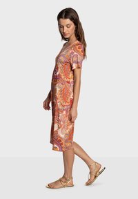 Robe mi-longue à motifs paisley dans des tons vibrants d'orange, rose et violet, à manches courtes, confectionnée dans un tissu lisse et léger.