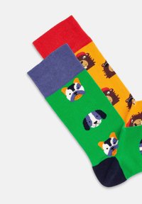 Calcetines coloridos con patrones de perros y animales. Un calcetín es verde con caras de perro; el otro es naranja con diseños de oso. Material de mezcla de algodón.