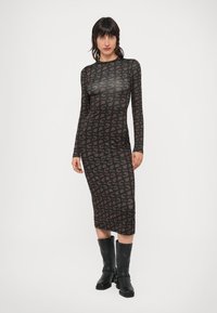 Μακρυμάνικό μαύρο φόρεμα με καφέ αφηρημένο σχέδιο, εφαρμοστή γραμμή, μήκος μέχρι το γόνατο, κατασκευασμένο από λείο, ελαφρώς διαφανές ύφασμα.