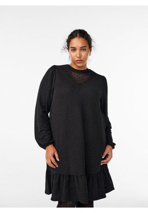 Black dress with a V-neckline, puffed long sleeves, textured fabric, and a ruffled hem. Underneath, a sheer black polka dot layer is visible.