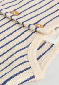 Helles beige gestricktes Kleidungsstück mit horizontalen marineblauen Streifen, Holzknöpfen und einem gerippten Kragen. Strukturierter Stoff mit einem weichen Erscheinungsbild.