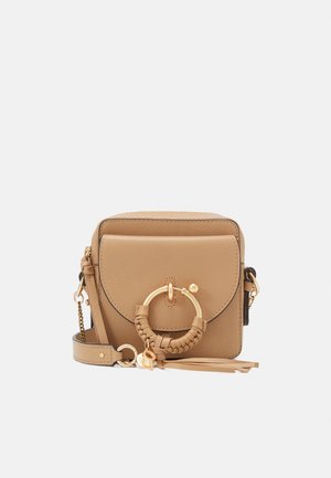 Petit sac bandoulière en cuir marron clair avec rabat devant, grand anneau doré et détail de sangle tressée, et bandoulière amovible avec ferrures dorées.