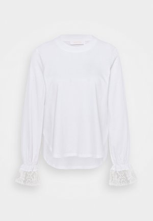 Hvid langærmet top lavet af blødt stof, med elastiske manchetter med detaljeret blondeaccent og rund halsudskæring.