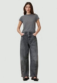 Randig kortärmad T-shirt i kombination med högmidjade, löst sittande mörkgrå jeans med fransade fållar och stora framfickor.