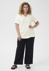 Wit v-hals t-shirt met korte mouwen, gecombineerd met zwarte wijde broek en zwarte slippers. Gladde textuur, eenvoudig ontwerp.