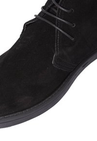 Stivale alla caviglia in suede nero con punta rotonda, parte superiore testurizzata e lacci neri. Presenta una suola in gomma resistente con sottili dettagli di cucitura.