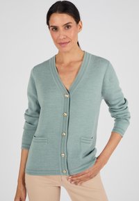 Cardigan verde menta realizzato in tessuto morbido con scollatura a V, bottoni dorati lungo il davanti e due tasche frontali. Maniche lunghe con polsini a coste.