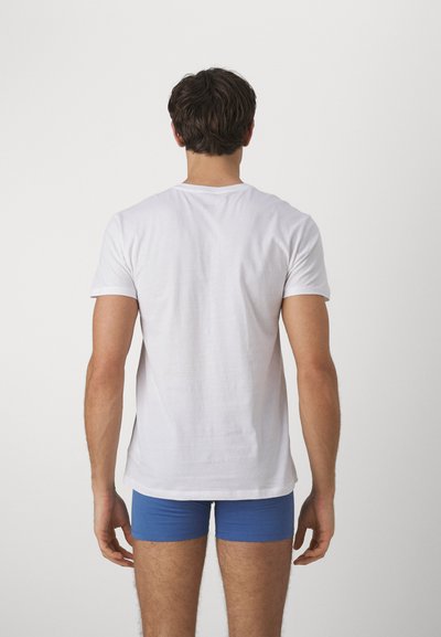 Balti medvilniniai trumpomis rankovėmis marškinėliai, derinami su mėlynais bokseriais. Audinys atrodo lygus, su klasikine apvaliomis kaklo iškirpte.