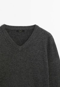 Pull col en V gris foncé avec col côtelé et manches longues, posé à plat sur un fond blanc.