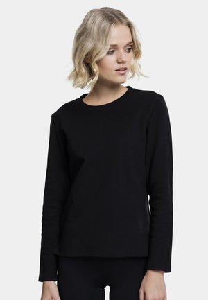 Svart langermet skjorte laget av mykt stoff med rund hals og slim fit, med minimal søm og uten synlige logoer.