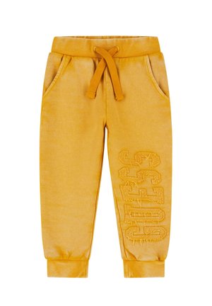 Pantalons de survêtement jaunes avec taille à cordon, poignets côtelés et poches latérales. Détails de logo texturé sur une jambe. Fini en tissu doux.