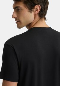 T-shirt nera a maniche corte, realizzata in cotone morbido, con un design a collo rotondo classico e una vestibilità rilassata. Stile minimalista e versatile.