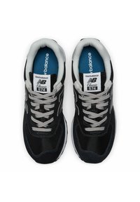 Pair of black and gray New Balance Classic 574 sneakers with gray laces and blue insoles, shown from top view on white background.