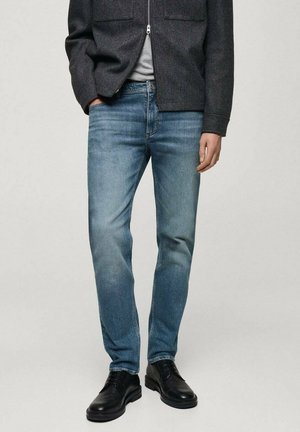 Blugi de culoare albastru deschis cu croială slim, având detalii decolorate. Asortați cu o jachetă gri și pantofi negri, creând un look casual.