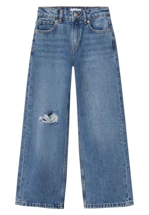 Vaqueros de mezclilla azul de pierna ancha con un agujero deshilachado en el muslo izquierdo, cierre frontal con botón y cremallera, y bolsillos delanteros.