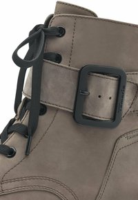 Bottine à lacets en suède gris avec une sangle à boucle noire. Comprend des lacets noirs et des œillets ronds, avec des détails de couture prononcés.