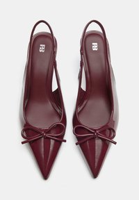 Burgundske patent usnjene čevlje s peto in konico, z dekorativno pentljo spredaj ter gladko, sijočo teksturo.