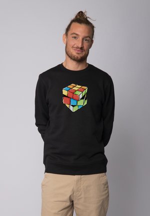 Sweatshirt noir avec un graphique en pixels d'un Rubik's Cube en rouge, vert, jaune et bleu. Matière douce et coupe classique.