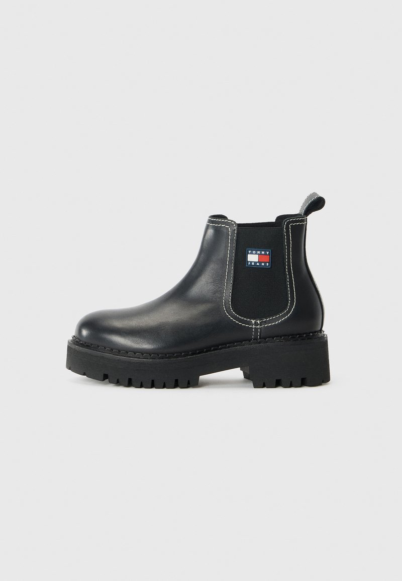 Bottines Chelsea noires en cuir, avec des panneaux latéraux en élasthanne, des coutures blanches contrastées et une semelle en caoutchouc texturée.