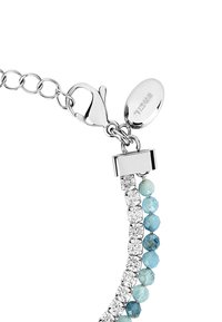 Pulsera de joyería con cierre de metal plateado y cadena. Presenta cuentas facetadas transparentes y de color azul claro dispuestas en patrones alternos.