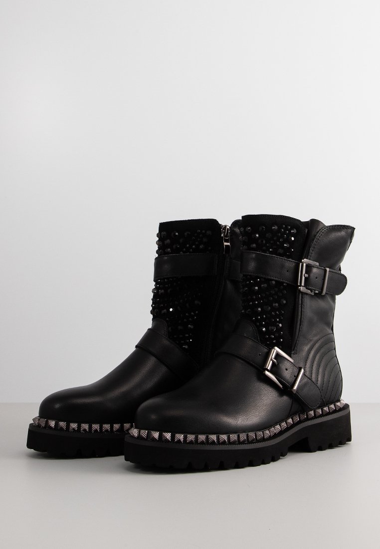 Botas de tobillo de cuero negro con un empeine texturizado que presenta adornos, hebillas y una suela con tachuelas. Detalle de cremallera en el costado.