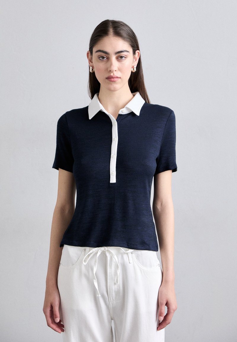 Navy short-sleeve polo shirt in soft fabric with a white collar and button placket, featuring a fitted design and smooth texture.