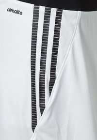 Pantalones cortos deportivos blancos con el logo negro de Climlite, que cuentan con tres rayas verticales negras decoradas con puntos. Textura suave, corte regular.