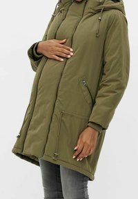 Parka vert olive avec fermeture éclair à l'avant, capuche à cordon de serrage, deux poches latérales et poignets côtelés. Confectionnée dans un tissu texturé et résistant à l'eau.