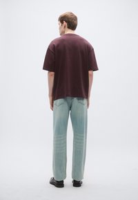 Mørkelilla oversized t-shirt med korte ærmer, kombineret med lyseblå denimjeans med falmet mønster og lige ben.