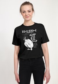 Černé bavlněné tričko s grafickou potiskem zachycujícím skrčenou postavu, stylizovaný text a bílé detaily, zdůrazňující manga téma.