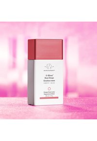 Square white bottle with a matte finish and a glossy red cap. Text labeling includes product name, volume, and key ingredients.