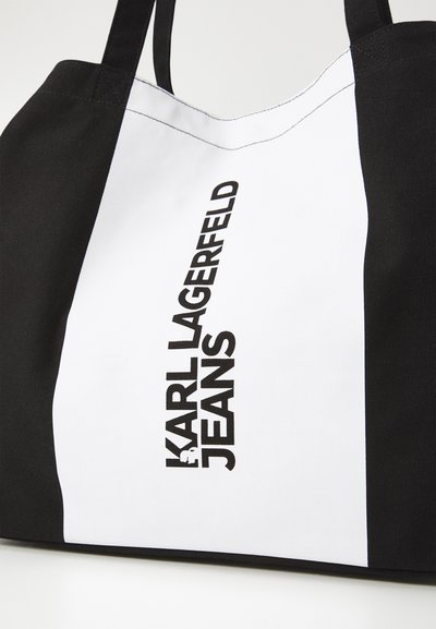 Черен и бял торбичка с текста "KARL LAGERFELD JEANS" с удебелени черни букви, с канвас текстура и контрастни цветови блокове.