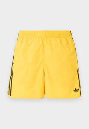 Φωτεινό κίτρινο μαγιό Adidas με ελαστική μέση, μαύρες λωρίδες στα πλάγια, πλαϊνές τσέπες και μαύρο λογότυπο Adidas trefoil στο αριστερό πόδι.